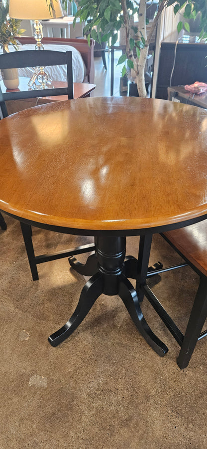 A round wooden table with a glossy brown finish and a black metal pedestal base.