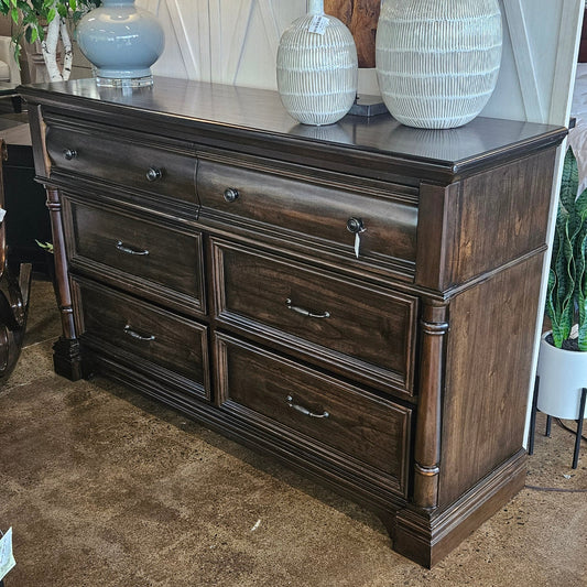 A dark brown wooden six-drawer dresser with metal handles.