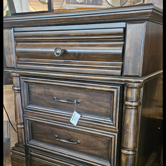 A dark brown wooden chest of drawers with a single drawer and two cabinet doors.