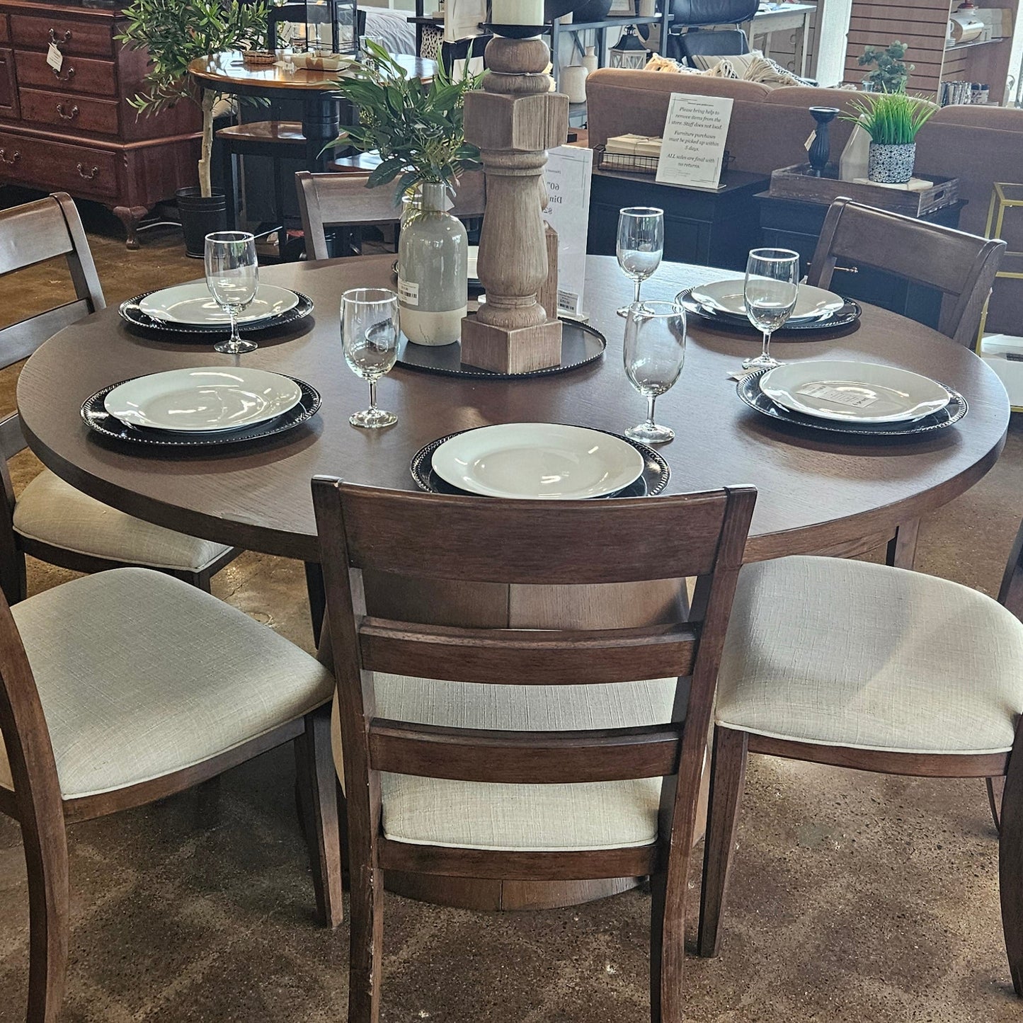A dining table set with dark wood chairs and white upholstered seats.