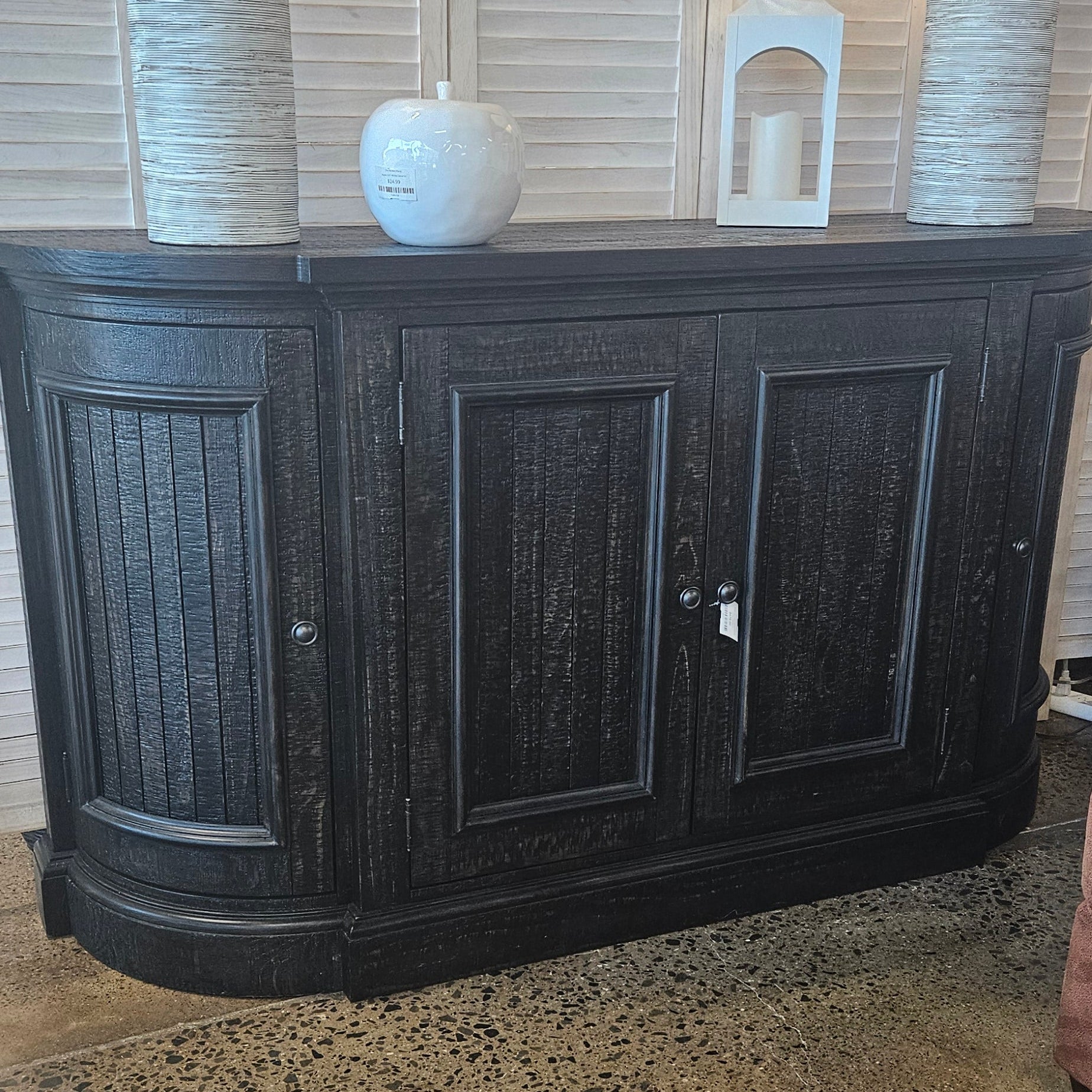 A dark wood cabinet with two upper doors and lower panel sections.