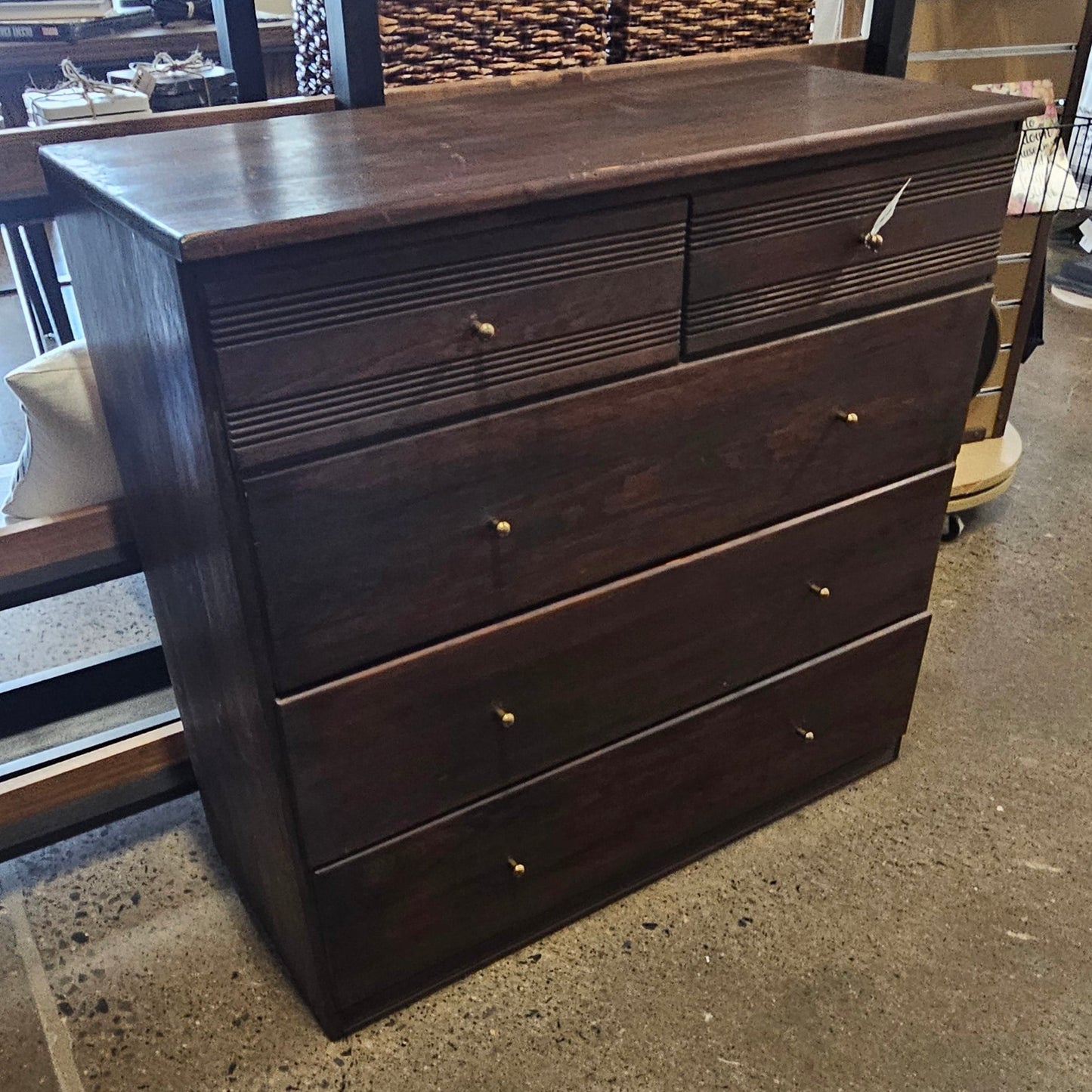 A dark brown wooden chest of drawers with multiple drawers and small round knobs.
