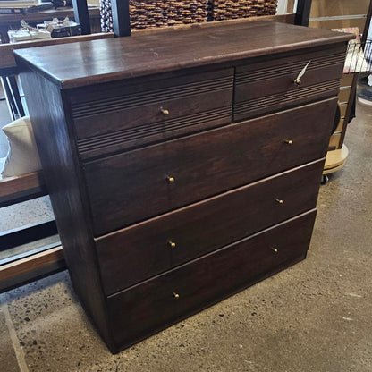 A dark brown wooden chest of drawers with multiple drawers and small round knobs.