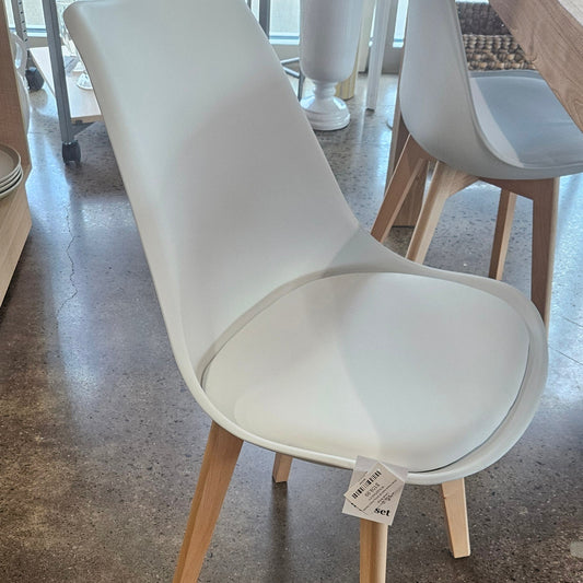 A modern white molded plastic chair with light natural wood legs.